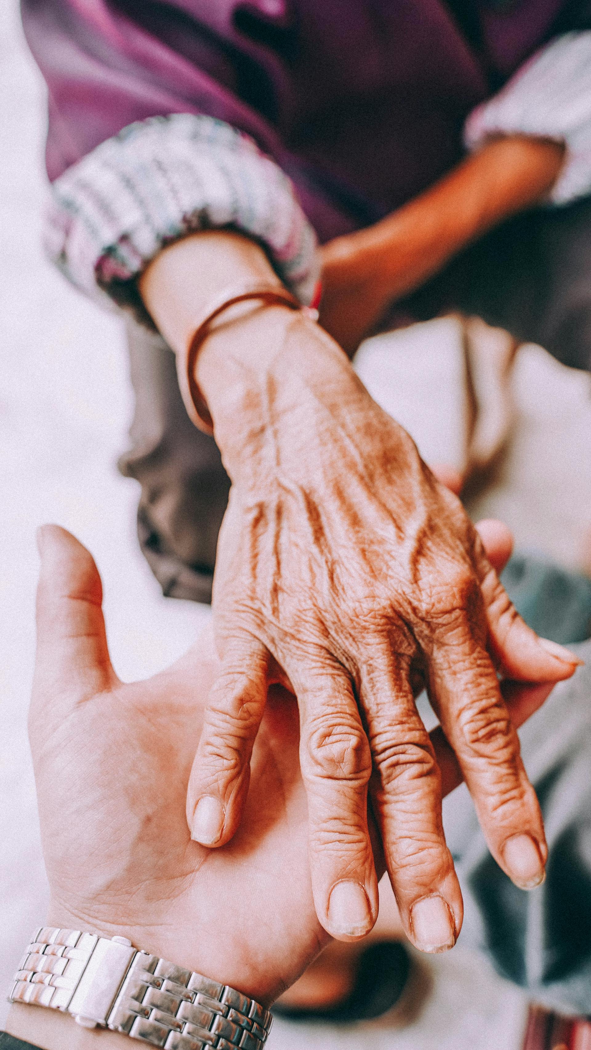 Des mains âgées tenues par des mains plus jeunes, symbole de l'accompagnement familial.