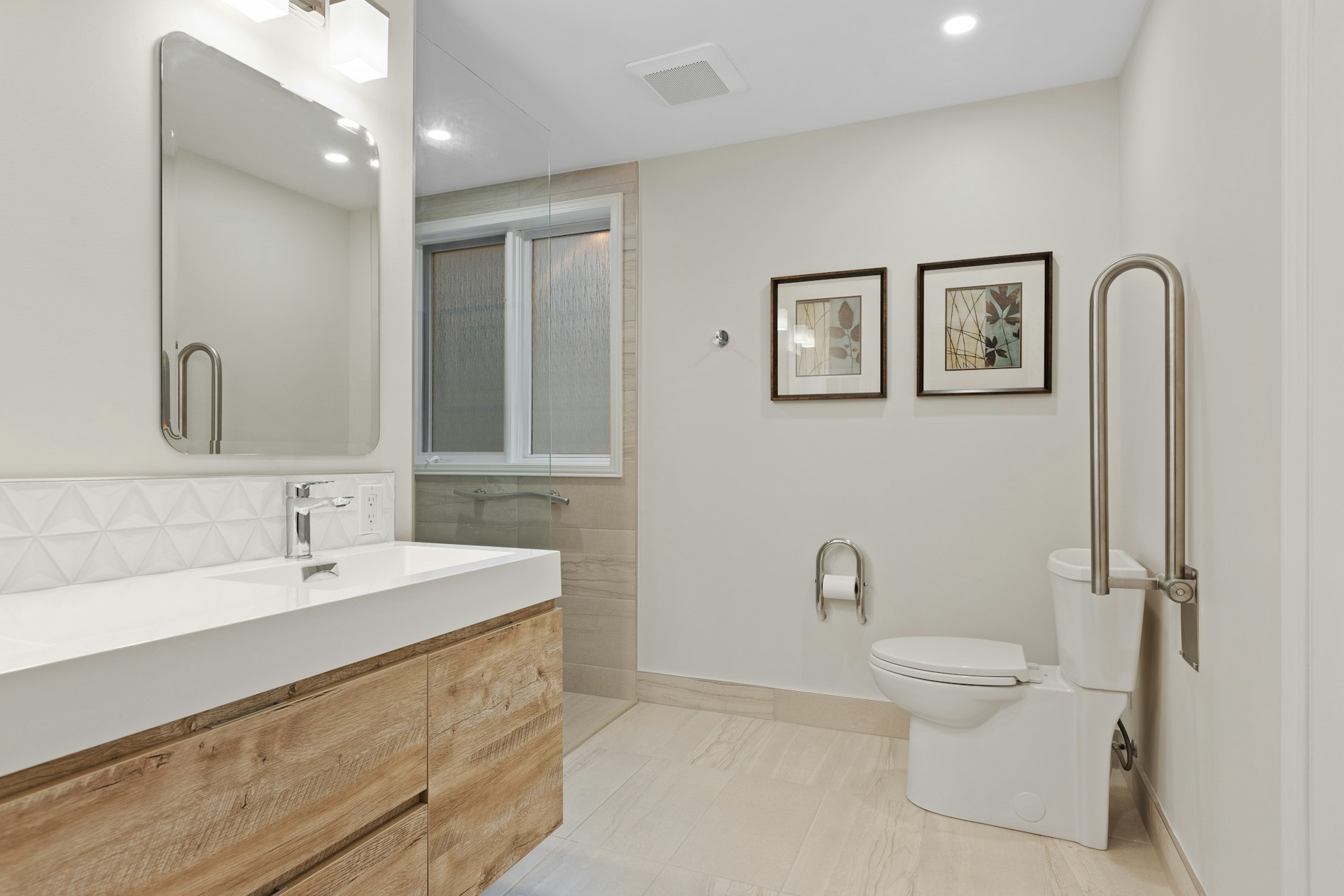 Salle d’eau adaptée : WC avec barre d’appui rabattable chromée, lavabo bois et large espace de circulation.